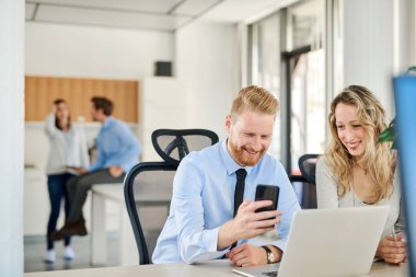 Ofiste çalışan iki arkadaşları, o bir şey ona onun Smartphone'da gösteriyor