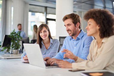 Masada oturan ve problem çözme arkadaşları. Dizüstü laptop arıyorum ve ona yardım iki kadın meslektaşları süre kullanan adam.