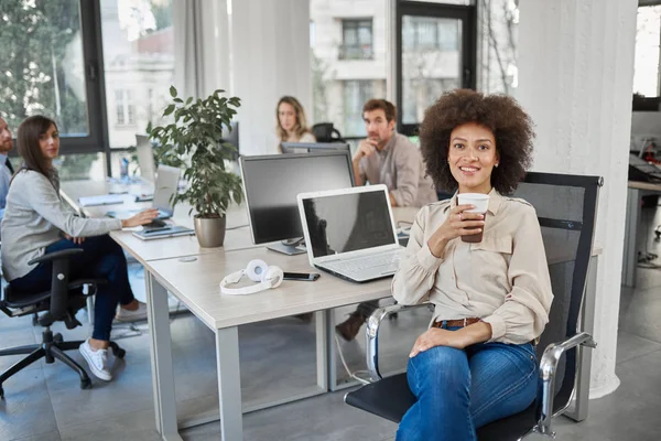 Sonriente Ceo Carrera Mixta Sentado Oficina Tomando Café Mientras Mira — Foto de Stock