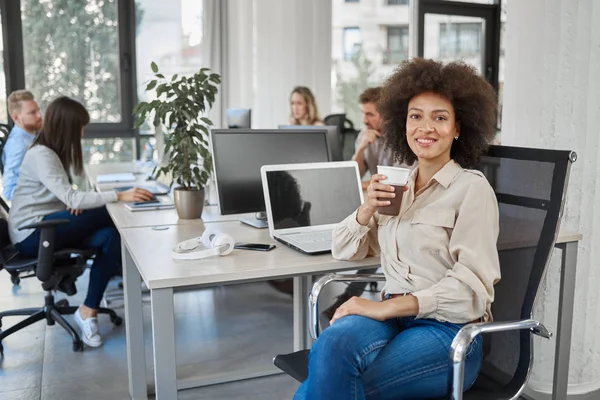 Sonriente Ceo Carrera Mixta Sentado Oficina Tomando Café Mientras Mira — Foto de Stock