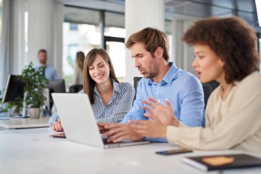 Masada oturan ve problem çözme arkadaşları. Dizüstü laptop arıyorum ve ona yardım iki kadın meslektaşları süre kullanan adam.
