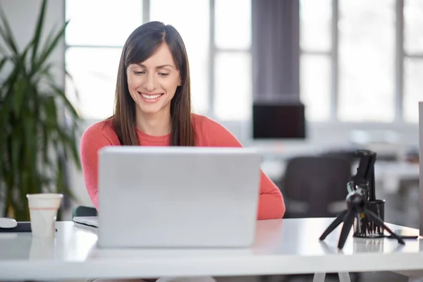 Bella donna d'affari caucasica sorridente seduta in ufficio moderno e utilizzando il computer portatile . — Foto Stock