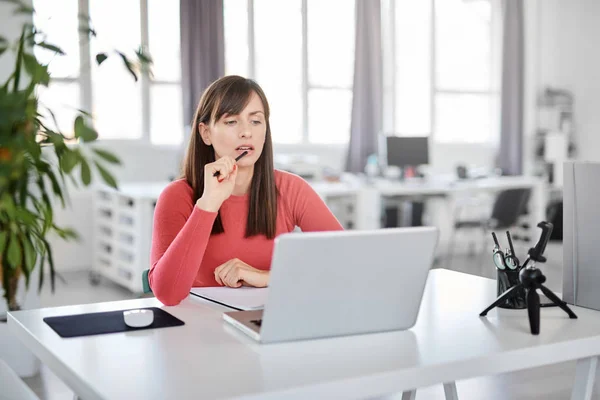 Frumoasă femeie de afaceri caucaziană zâmbitoare care stă în biroul modern și folosește laptop . — Fotografie, imagine de stoc