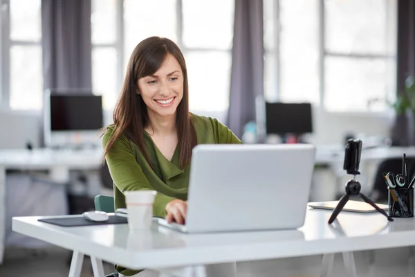 Bella donna d'affari caucasica sorridente seduta in ufficio moderno e utilizzando il computer portatile . — Foto Stock