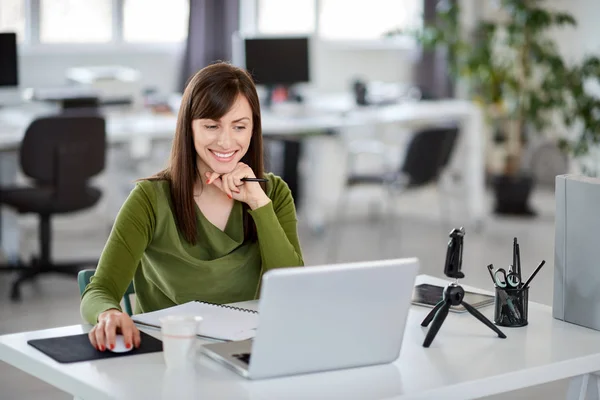 Hermosa mujer de negocios caucásica sonriente sentada en la oficina moderna y usando el ordenador portátil . — Foto de Stock