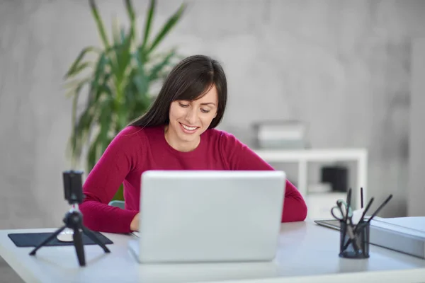 Piękna kobieta interesu Kaukaska uśmiechający się siedzi w nowoczesnym biurze i komputera przenośnego. — Zdjęcie stockowe