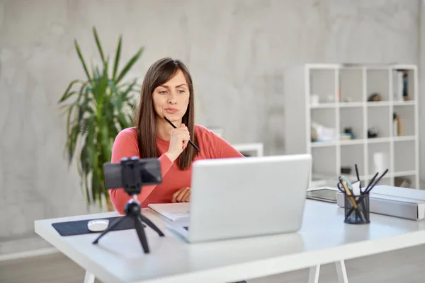 Beautiful Caucasian businesswoman with brown hair and dressed casual sitting in office and trying to solve a problem. In front of her laptop. — Stock Photo, Image