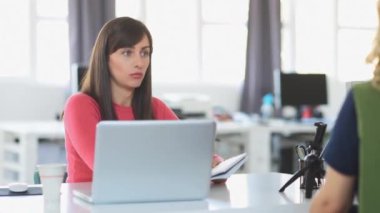 Young businesswoman sitting at modern office and using technology.