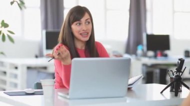 Young businesswoman sitting at modern office and using technology.