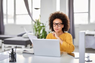 Modern ofiste otururken ciddi karışık ırk çekici iş kadını akıllı rahat holding evrak giyinmiş.