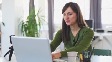 Güzel Kafkas iş kadını modern ofiste dizüstü bilgisayar kullanarak akıllı rahat giyinmiş.