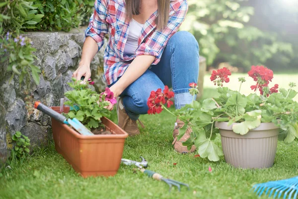 彼女の裏庭に花を植える作業服の白人女性. — ストック写真