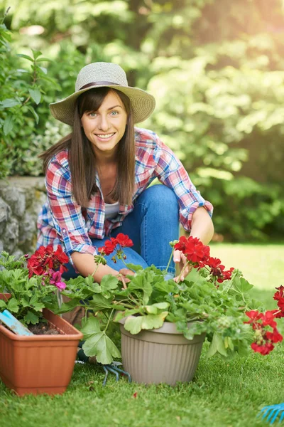 ゴージャスな白人ブルネットの完全な長さは、彼女の裏庭にしゃがんで花を植えます. — ストック写真