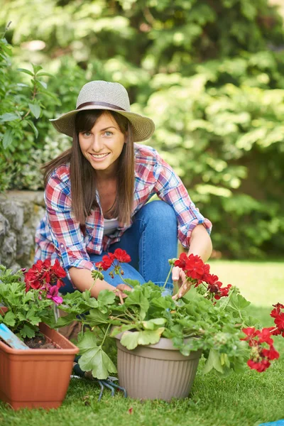 ゴージャスな白人ブルネットの完全な長さは、彼女の裏庭にしゃがんで花を植えます. — ストック写真