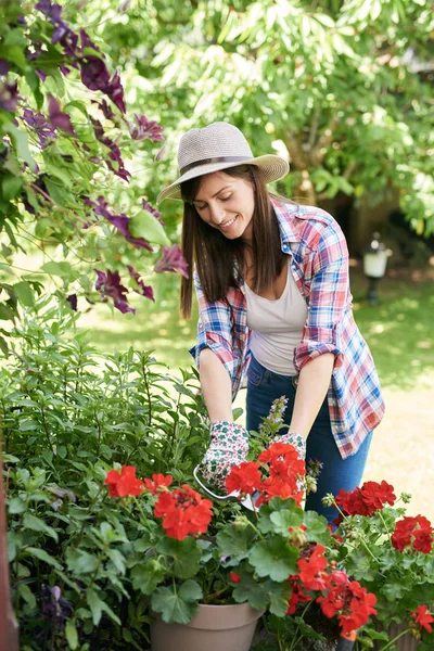 作業服と彼女の裏庭に帽子剪定花で美しい笑顔白人ブルネット. — ストック写真