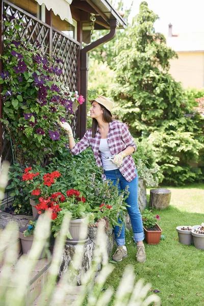 ガーデニング手袋と裏庭で彼女の花の世話をする作業服で美しい笑顔白人ブルネット — ストック写真