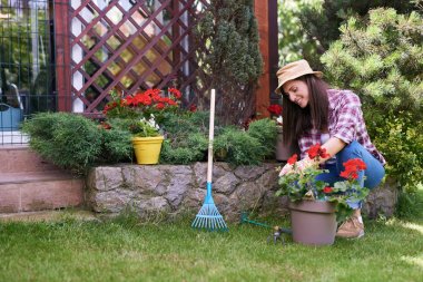 Güzel gülümseyen Kafkas esmer çalışma giysileri ve şapka ile çiçek onun arka bahçesinde budama ile.