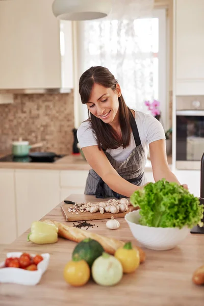 Mooie hardwerkende huisvrouw die salade uit de kom terwijl hij in de keuken staat. Zelf gemaakt diner voorbereidings concept. — Stockfoto