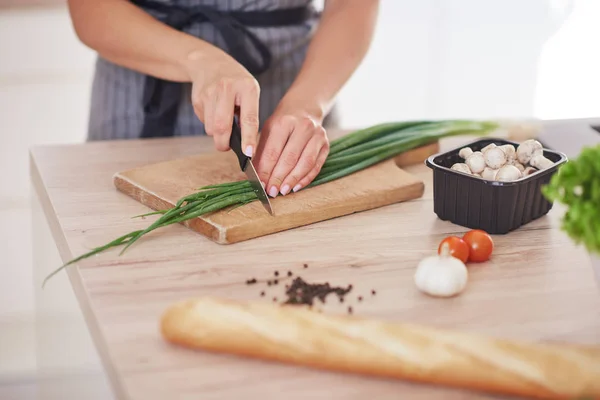 Uitgesneden beeld van vrouw hakken leek op Cutting Board in de keuken. — Stockfoto