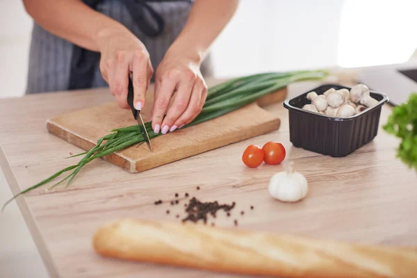 Uitgesneden beeld van vrouw hakken leek op Cutting Board in de keuken. — Stockfoto