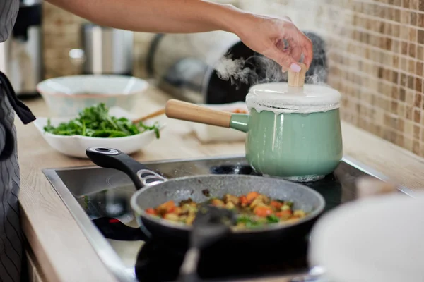 Toegewijde blanke vrouw opening kookpot. Vegetarisch diner voorbereidings concept. — Stockfoto