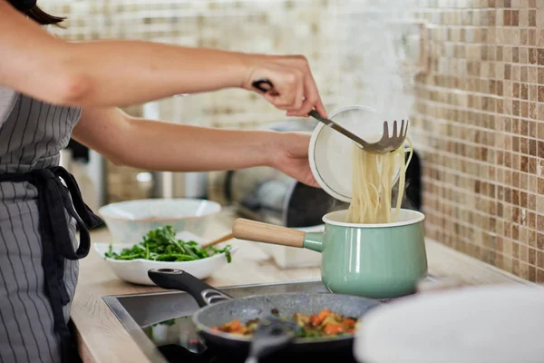 Mulher caucasiana de avental em pé ao lado do fogão e preparando espaguete. Preparação do conceito de alimento italiano . — Fotografia de Stock