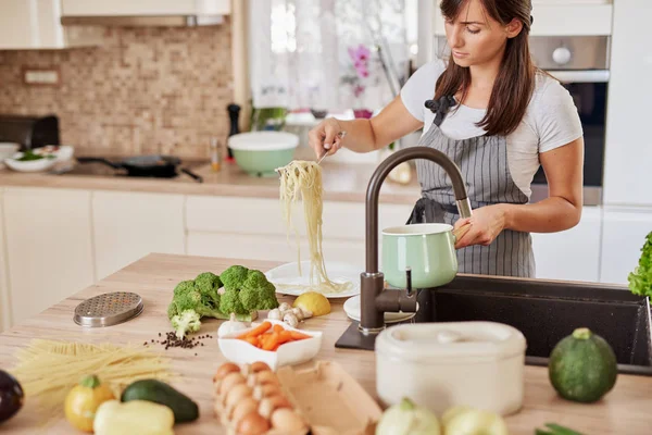 Mulher caucasiana de avental em pé na cozinha e colocando espaguete na placa. Preparação do conceito de alimento italiano . — Fotografia de Stock