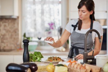 Sevimli Kafkas esmer apron mutfakta ayakta ve taze lezzetli makarna tuz ekleyerek. İtalyan gıda konseptinin hazırlanması.