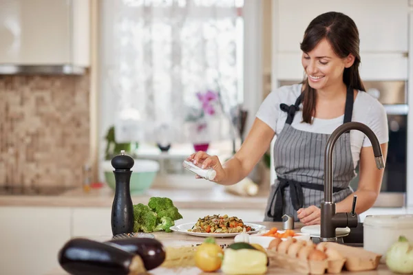 Linda morena caucásica en delantal de pie en la cocina y añadiendo sal en pasta fresca deliciosa. Preparación del concepto de comida italiana . — Foto de Stock