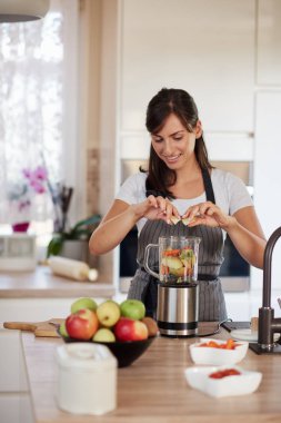Mutfakta dururken blender sebze ve meyve koyarak önlük güzel Kafkas gülümseyen kadın.