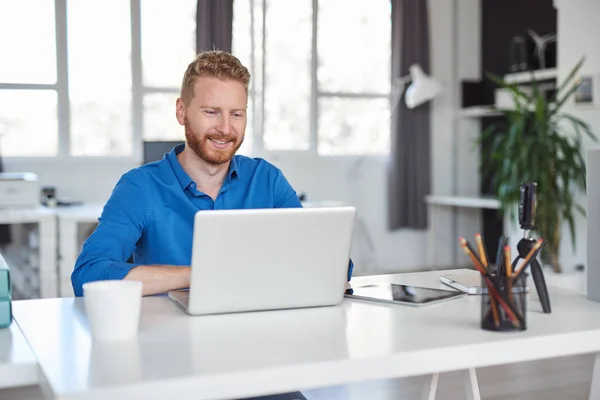 Jonge Kaukasische werknemer zittend in kantoor en typen op de laptop. Bedrijfsconcept opstarten. — Stockfoto