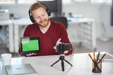 Yakışıklı Kafkas çalışanı internet üzerinden sunum yapıyor. Ellerde tablet ve baş kulaklıkvardır. İş konseptini başlatın.