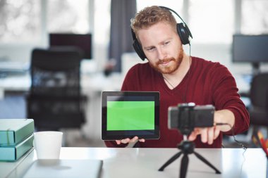 Yakışıklı Kafkas çalışanı internet üzerinden sunum yapıyor. Ellerde tablet ve baş kulaklıkvardır. İş konseptini başlatın.