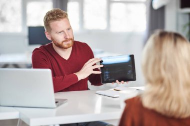 Yakışıklı Kafkas yöneticisi, çalışan iş stratejisine tablette gösteriyor. İş konseptini başlatın.