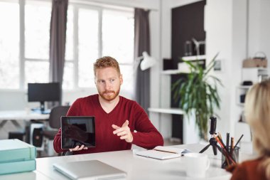 Yakışıklı Kafkas yöneticisi, çalışan iş stratejisine tablette gösteriyor. İş konseptini başlatın.