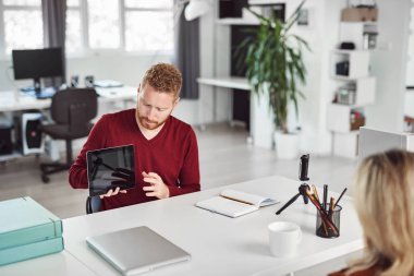 Yakışıklı Kafkas yöneticisi, çalışan iş stratejisine tablette gösteriyor. İş konseptini başlatın.