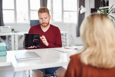 Yakışıklı Kafkas yöneticisi, çalışan iş stratejisine tablette gösteriyor. İş konseptini başlatın.