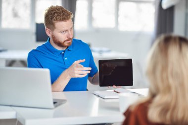 Yakışıklı Kafkas yöneticisi, çalışan iş stratejisine tablette gösteriyor. İş konseptini başlatın.