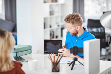 Yakışıklı Kafkas odaklı çalışan tablet tutan ve hisse senedi satın almak için kadın müşteri ikna etmeye çalışıyor.
