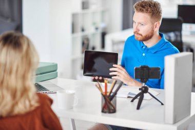 Yakışıklı Kafkas odaklı çalışan tablet tutan ve hisse senedi satın almak için kadın müşteri ikna etmeye çalışıyor.