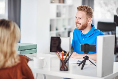 Yakışıklı Kafkas odaklı çalışan tablet tutan ve hisse senedi satın almak için kadın müşteri ikna etmeye çalışıyor.