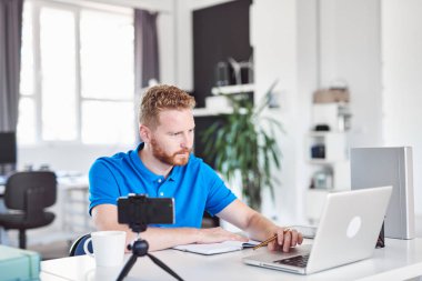 Kendini işine adamış çalışkan Kafkas çalışanı modern ofiste oturuyor ve not defterine bir şeyler yazıyor.