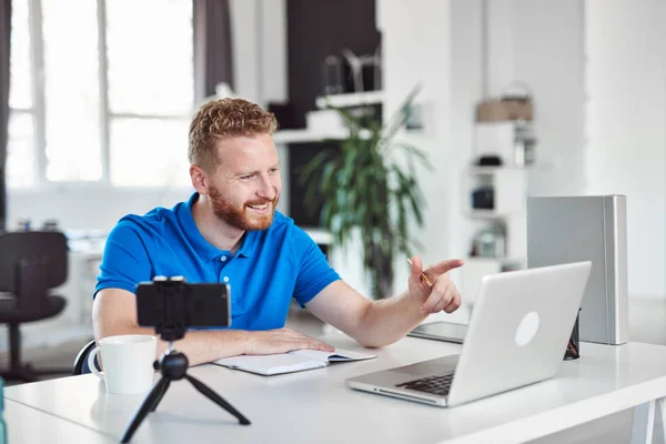 Empleado caucásico dedicado a trabajar duro sentado en una oficina moderna y escribiendo algo en un cuaderno . — Foto de Stock