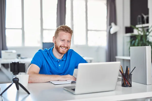 Jeune employé caucasien assis au bureau et tapant sur un ordinateur portable. Concept de création d'entreprise . — Photo