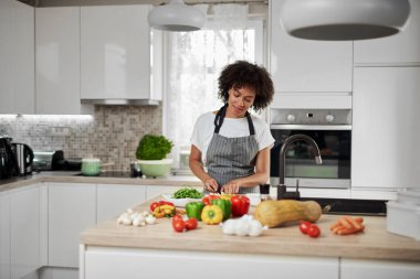 Mutfakta ayakta ve mantar doğranan önlük Muhteşem karışık ırk ev kadını. Mutfak tezgahında sebze her türlü vardır.
