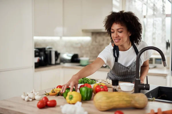 Bela dona de casa de raça mista chegando para o pimentão verde enquanto está na cozinha. Preparação para jantar.B . — Fotografia de Stock
