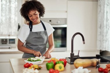 Mutfakta ayakta ve mantar doğranan önlük Muhteşem karışık ırk ev kadını. Mutfak tezgahında sebze her türlü vardır.