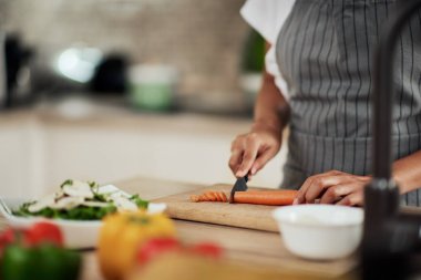 Mutfakta ayakta ve mantar doğranan önlük karışık ırk kadın yakın çekim.