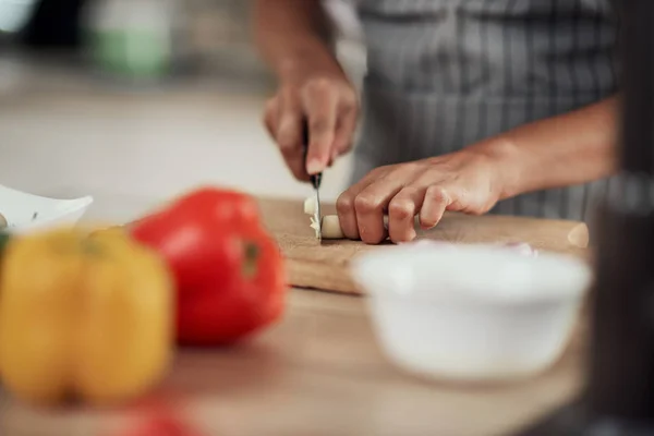 Primer plano de la mujer de raza mixta en delantal de pie en la cocina doméstica y cortar el ajo . — Foto de Stock