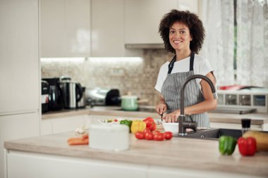 Mutfakta ayakta ve mantar doğranan önlük Muhteşem karışık ırk ev kadını. Mutfak tezgahında sebze her türlü vardır.